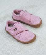 Froddo barefoot wooly children's shoe in pink standing on a pastel coloured blanket. A natural wooly shoe with a velcro fastener for a secure fit and a dark brown grippy and available at Babipur