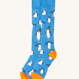 A close up of the Frugi dark blue penguin brilliant boot sock showing the penguin print and orange toe and heel detail on organic cotton fabric