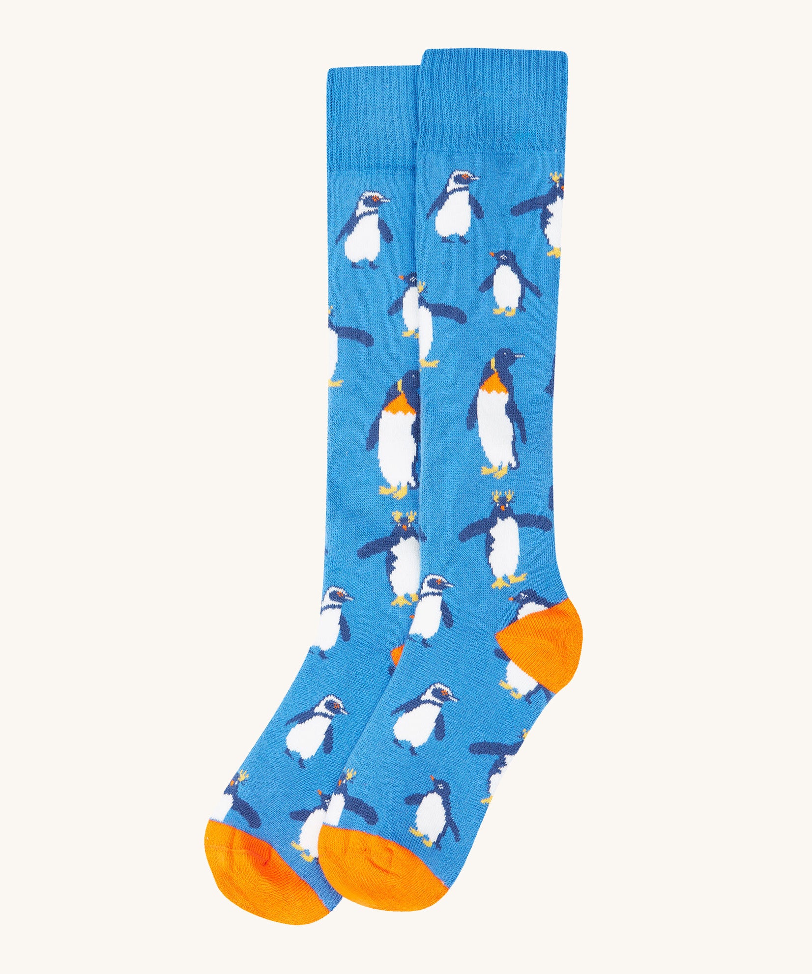 A close up of the Frugi dark blue penguin brilliant boot sock showing the penguin print and orange toe and heel detail on organic cotton fabric