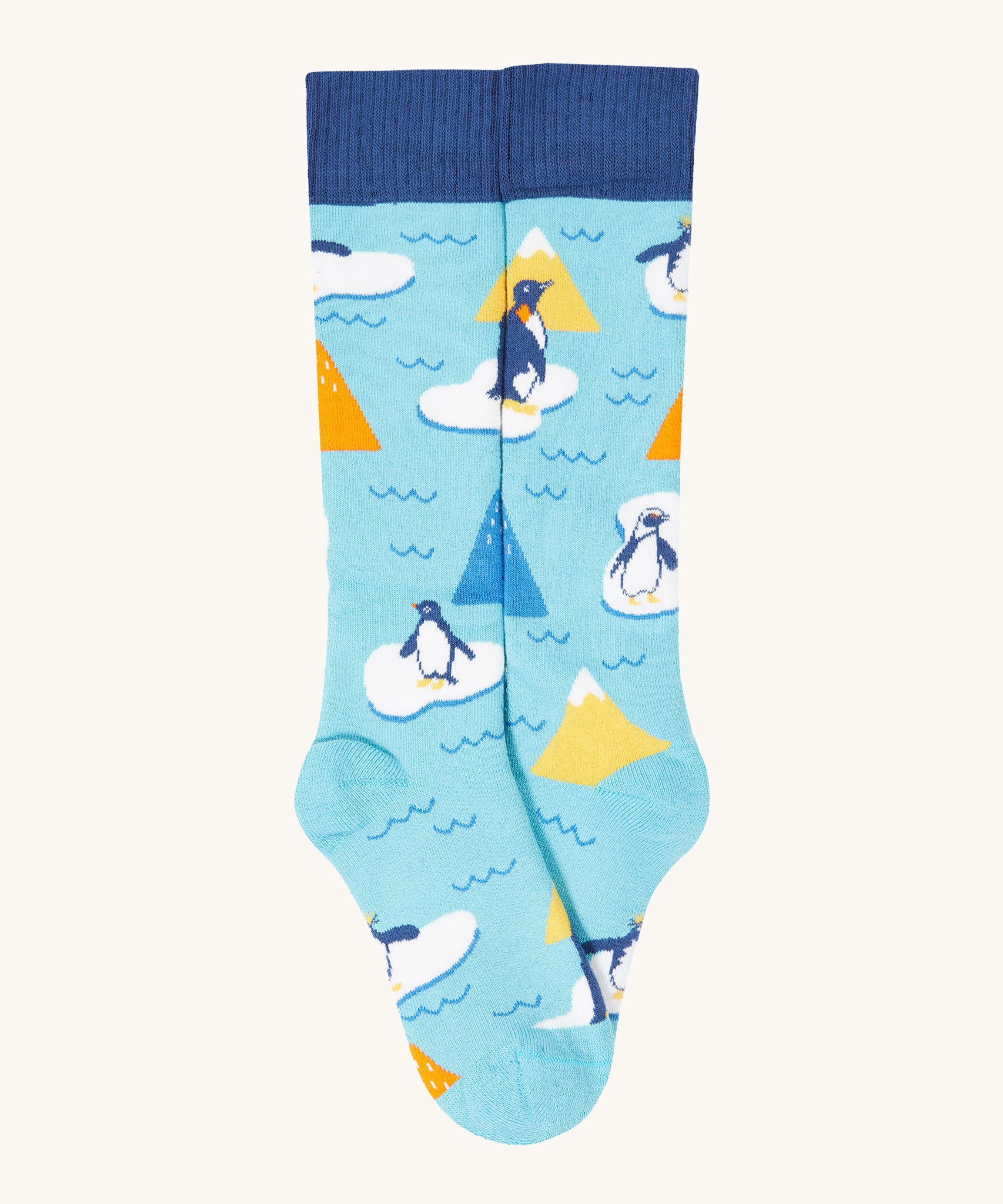 A close up of the Frugi light blue penguin brilliant boot sock showing the penguin print and dark blue cuff detail on organic cotton fabric
