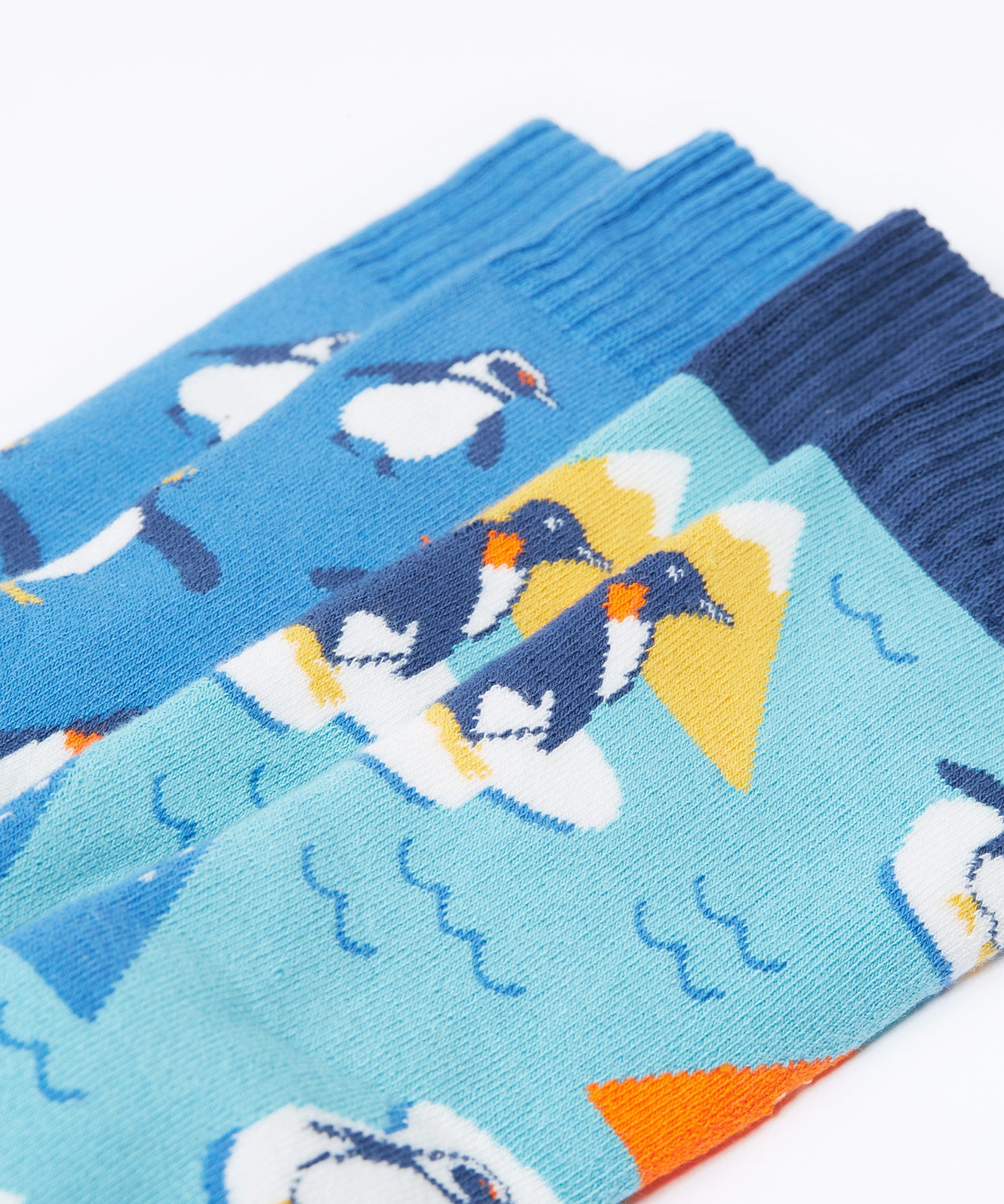 A close up of the Frugi 2 pack penguin brilliant boot socks showing the print detail on blue organic cotton fabric
