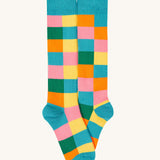 A close up of the rainbow Frugi brilliant boot sock showing the multicoloured check print with light blue toe and heel detail organic cotton fabric