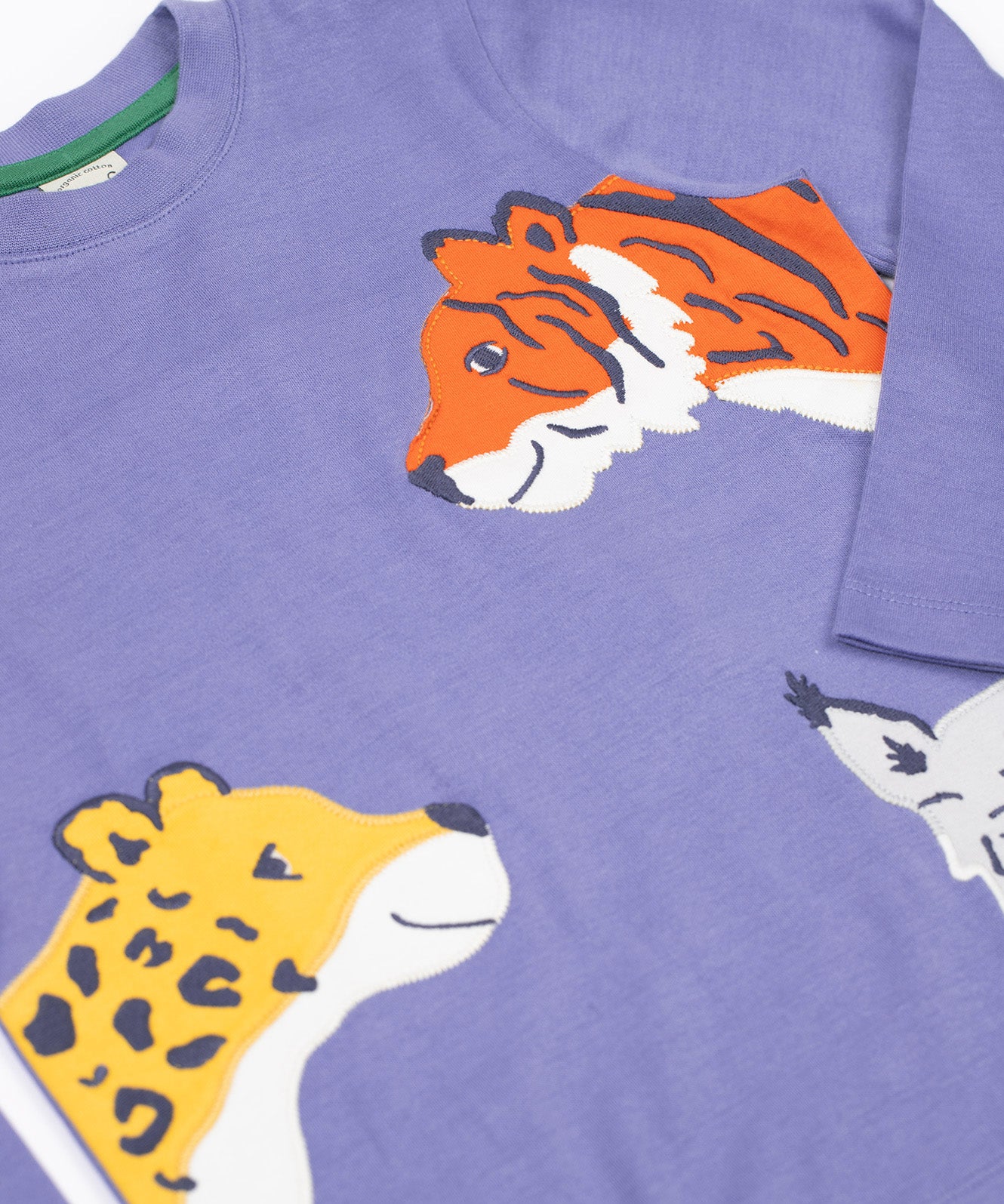 A close up of the front of the Frugi Adventure big cats Applique organic cotton long sleeved top. This top features three big cat appliques on a grape purple coloured background. This top is a part of a wide range of organic cotton clothing for children available here at Babipur.