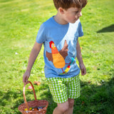 A child wearing the Frugi Avery appliqué t-shirt, a soft GOTS organic cotton light blue top with a chicken riding a skateboard appliqué on the front.