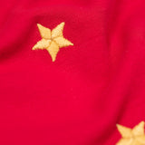 A close up of the gold embroidered star detail on the front of the Frugi Berry Red Reindeer Terrific Circular Organic Cotton long sleeved kids Top. A red coloured children's top with a festive reindeer applique and gold stars on the front. This top is a part of a wide range of organic cotton clothing for children available here at Babipur.