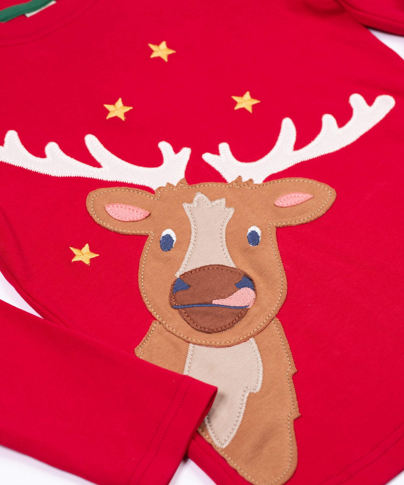 A close up of the reindeer applique on the front of the Frugi Berry Red Reindeer Terrific Circular Organic Cotton long sleeved kids Top. A red coloured children's top with a festive reindeer applique and gold stars on the front. This top is a part of a wide range of organic cotton clothing for children available here at Babipur.