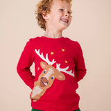 A child wearing the Frugi Berry Red Reindeer Terrific Circular Organic Cotton long sleeved kids Top available at Babipur. A red coloured children's top with a festive reindeer applique and gold stars on the front.