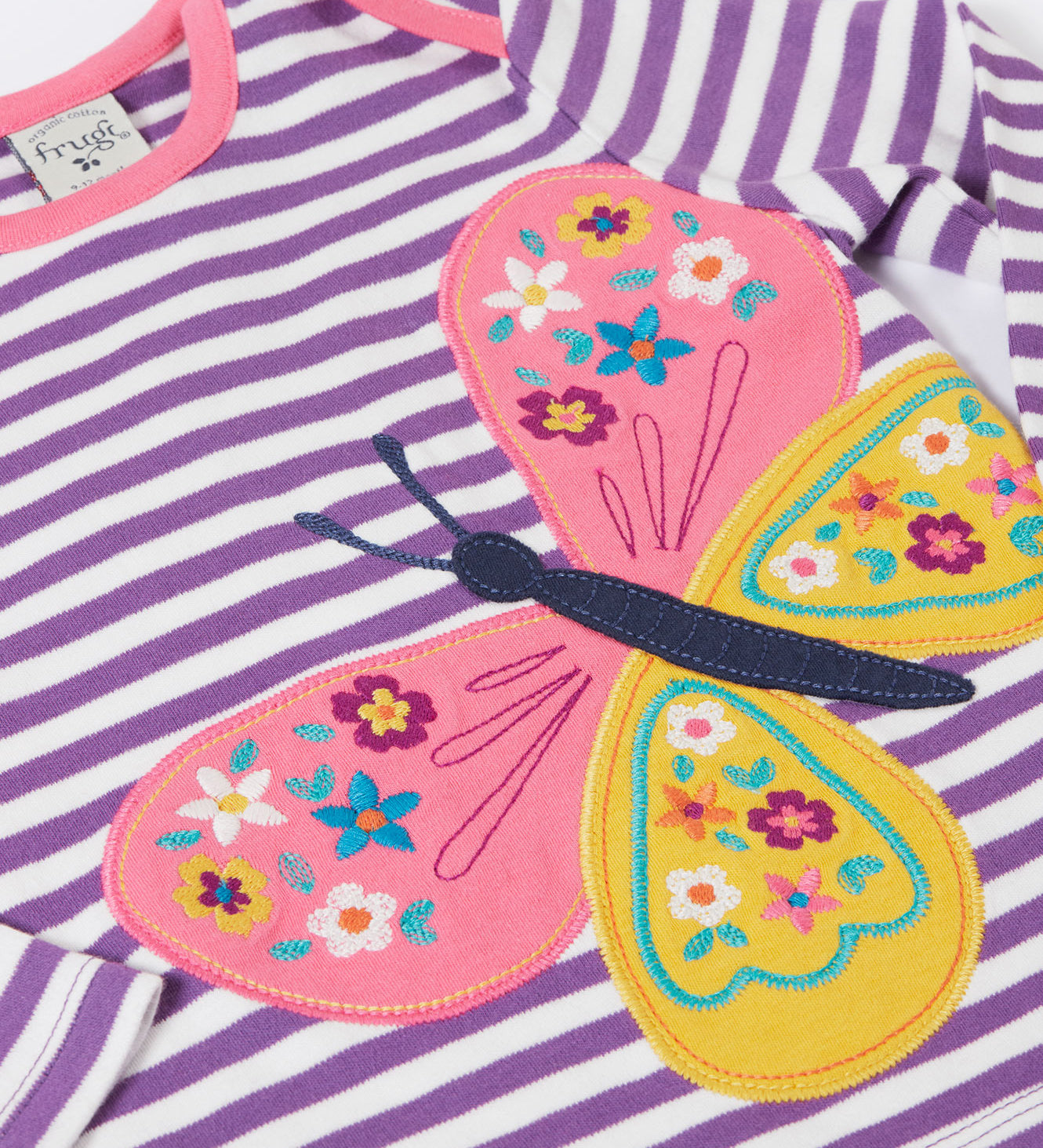 A close up of the butterfly applique detail on the front of the Frugi Children's organic cotton Bobby butterfly Applique purple striped  long sleeved Top. The top has a violet purple and white stripe background with a large decorated butterfly applique on the front. This top is a part of a wide range of organic cotton clothing for children available here at Babipur.