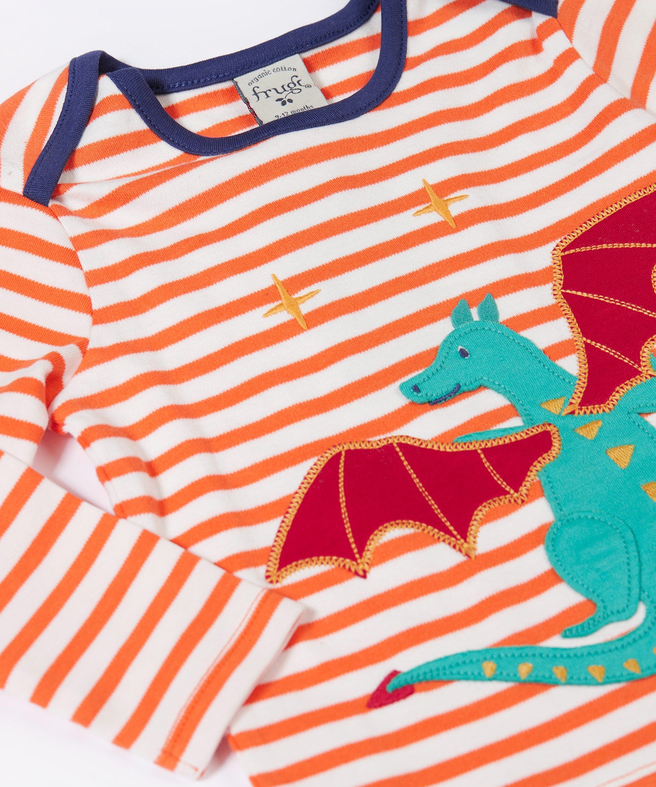 A close up of the Dragon applique on the Frugi Children's Bobby dragon Applique orange and white striped long sleeved Top. This top is a part of a wide range of organic cotton clothing for children available here at Babipur.
