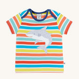 Frugi Bobster Applique T-Shirt in a Sea Rainbow Stripe print laid flat, featuring an embroidered Shark in the centre, and popper fastenings at the top.