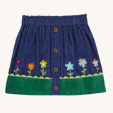 A Frugi Cara cord children's skirt in ink blue with flower and grass details.
