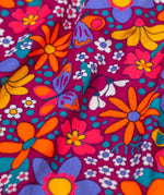 A close up of the print detail on the Frugi Elsie Organic Printed Cord Dress with a Retro Floral print design. This cord dress is a part of a wide range of organic cotton clothing for children available here at Babipur.