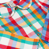 A close up of the collar and button closure on the front of the Frugi Rainbow Check Organic Cotton Ffion Dress. The dress has a rounded collar details and button closure on the front. This festive kids dress is a part of a wide range of organic cotton clothing for children available here at Babipur.