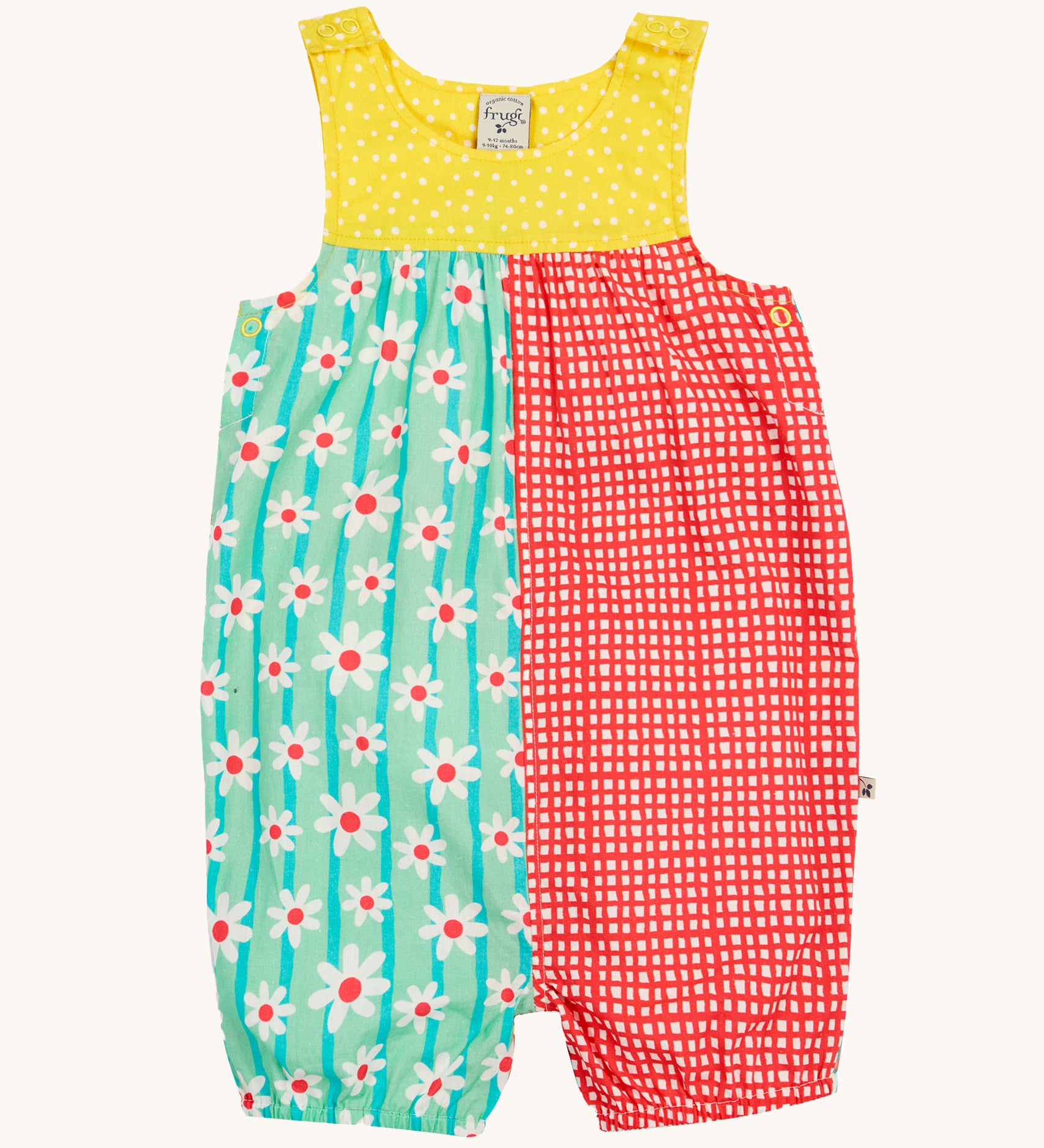 Frugi Summer Printed Dungaree in the Rainbow Hotchpotch print laid flat, showing a patchwork type design in yellow, red and green with daisies, featuring popper fastenings.