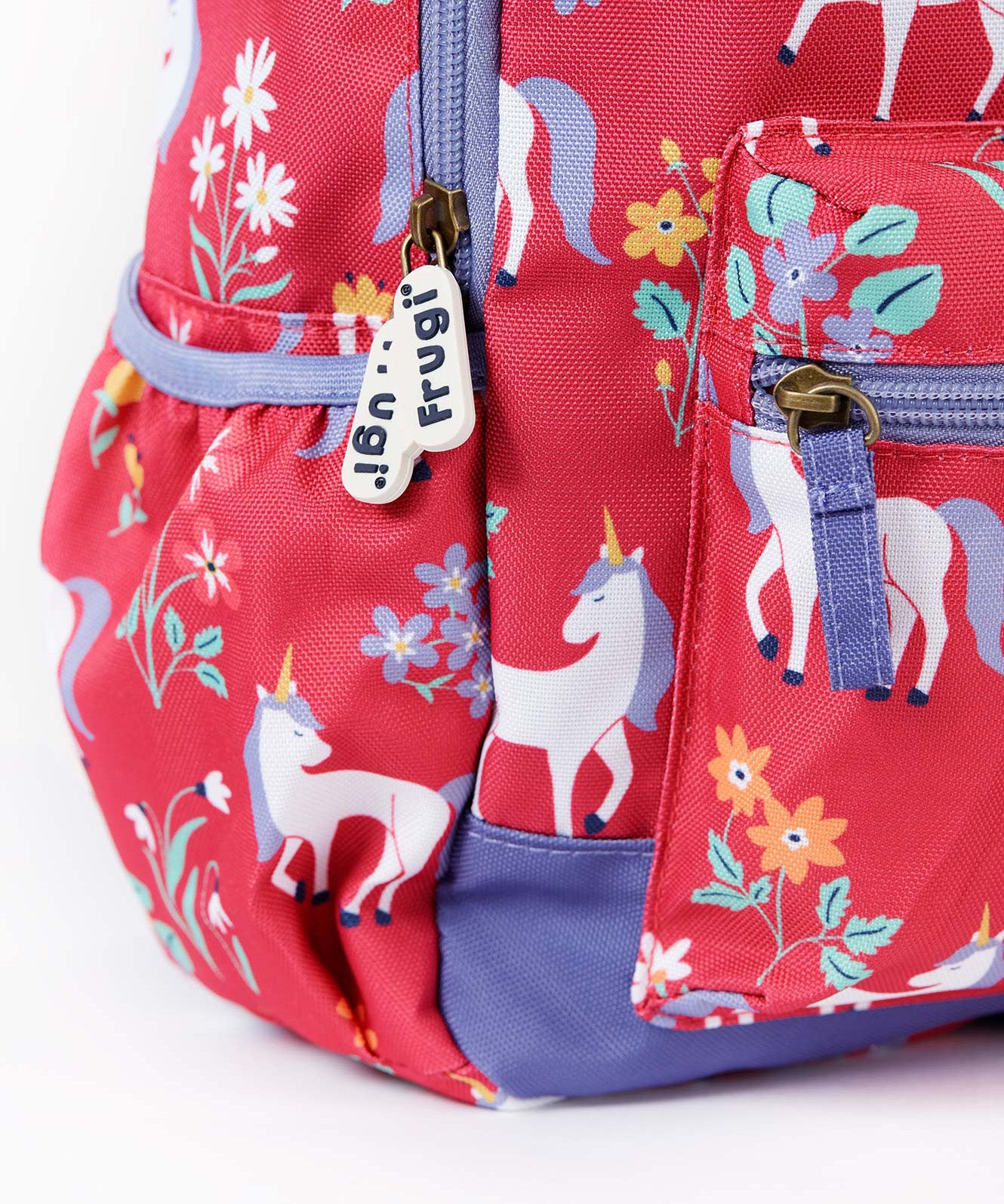 A close up of the Frugi rose unicorn floral explorer backpack showing the bottle holder, compartment zips and gentle white unicorn print detail