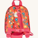The back of the Frugi little adventures fun flowers backpack showing the reflective stars on the shoulder straps and the pink rein clipped to the top of the bag