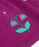 A close up of the flower details on the skirt of the Frugi Damson purple Flowers Organic Cotton Vali Corduroy children's Dress. This cord kids dress is a part of a wide range of organic cotton clothing for children available here at Babipur.