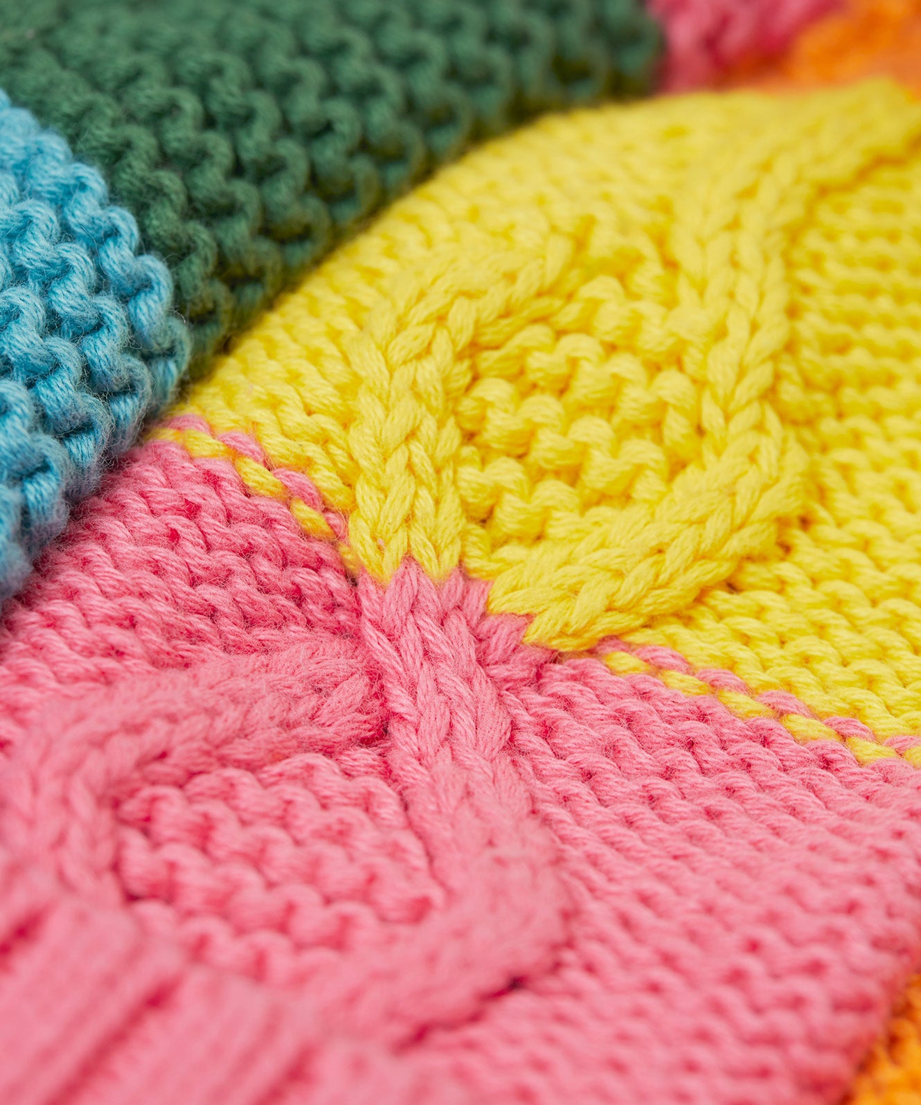 A close up of the Frugi kids cable knit rainbow check bobble hat. Showing the thick knit detail