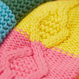 A close up of the Frugi kids cable knit rainbow check bobble hat. Showing the thick knit detail