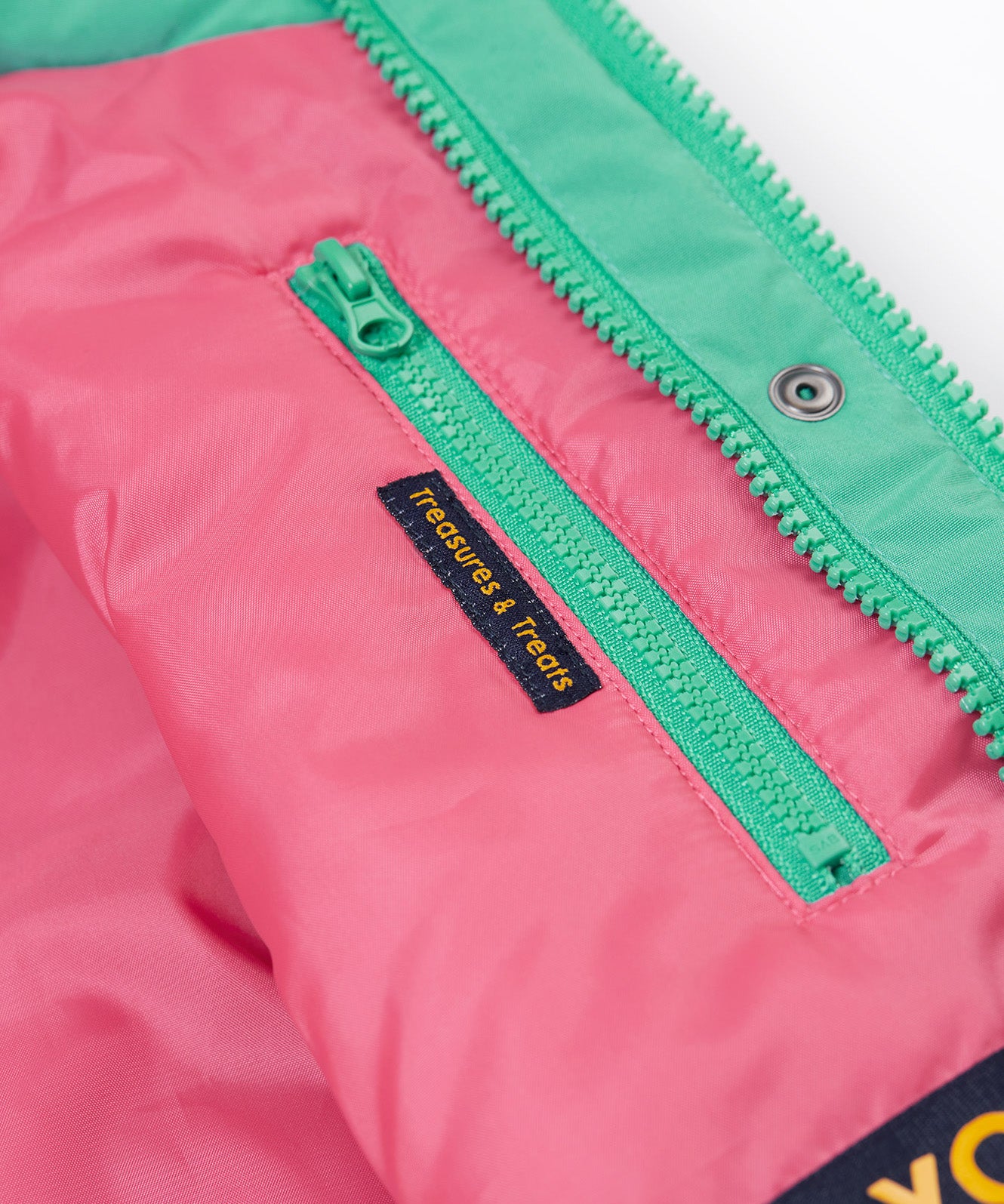 A close up of the Frugi kids 3 in 1 rambler coat in dragon/mushroom showing the hidden side pocket and bright turquoise zip detail on the inside of the coat on pink post consumer recycled polyester fabric