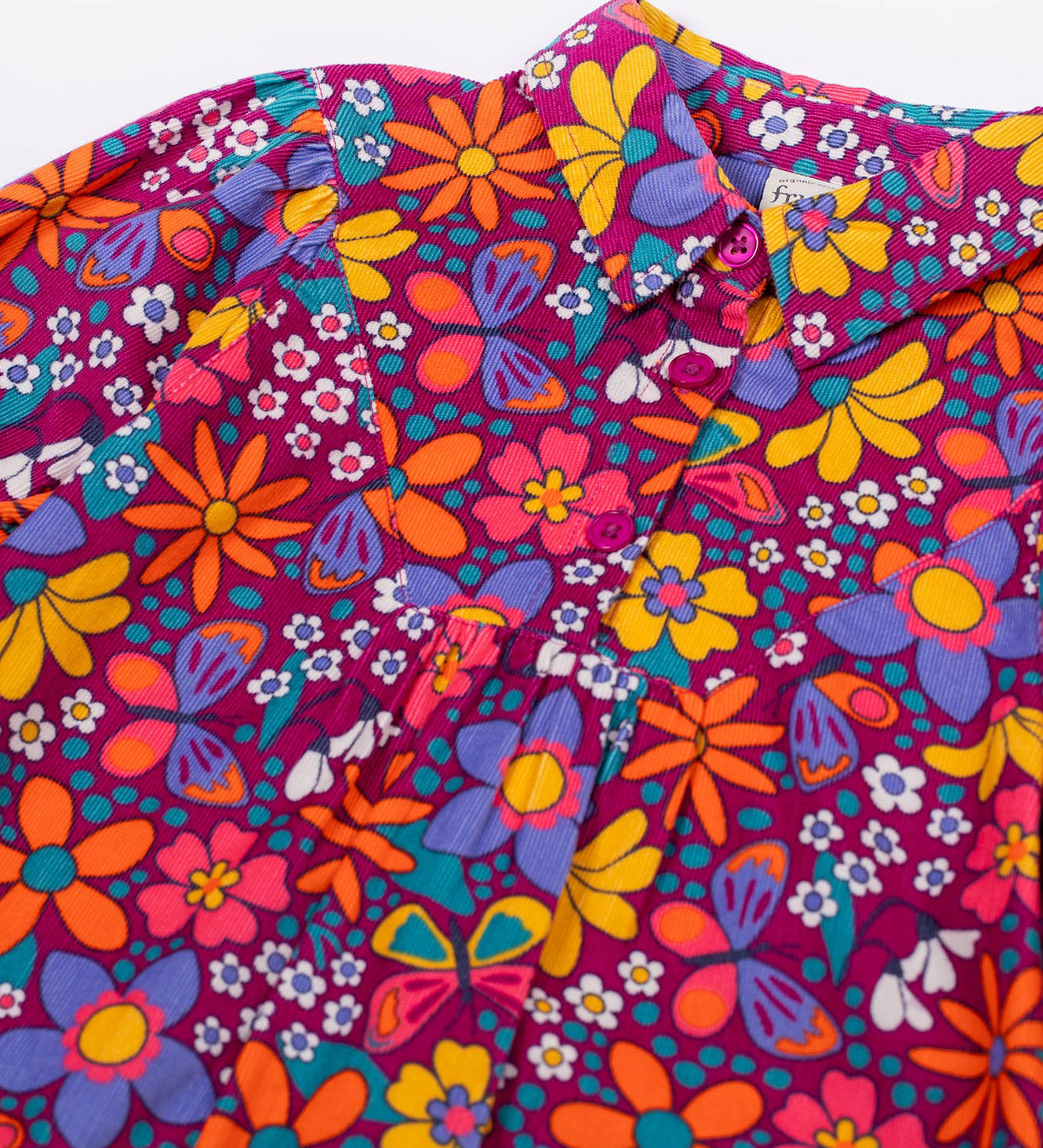 A close up of the button closure on the Frugi Elsie Organic Printed Cord Dress with a Retro Floral print design. This cord dress is a part of a wide range of organic cotton clothing for children available here at Babipur.