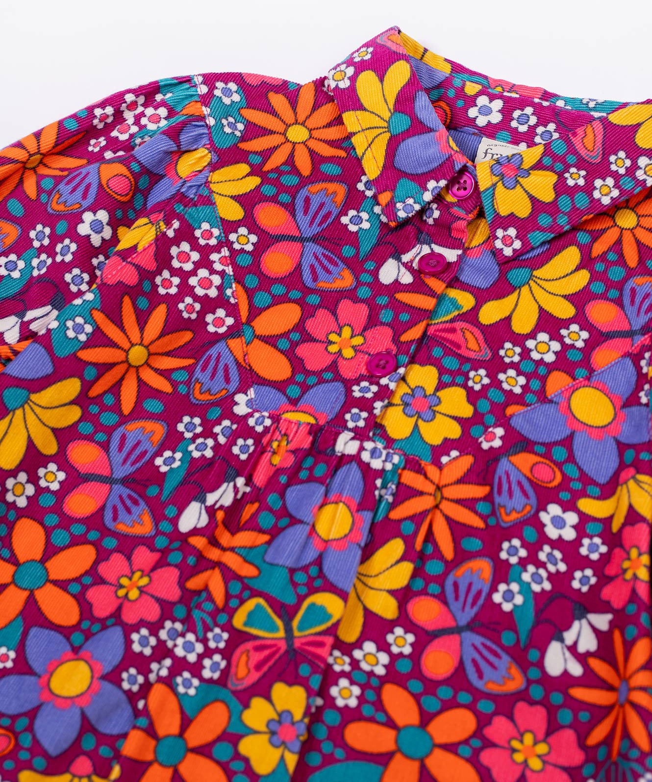 A close up of the button closure on the Frugi Elsie Organic Printed Cord Dress with a Retro Floral print design. This cord dress is a part of a wide range of organic cotton clothing for children available here at Babipur.