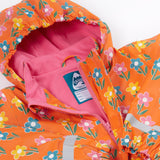 A close up of the Frugi kids fun flowers puddle buster coat showing the multicolour flowers on orange waterproof material. Features a full length zip and velcro fasteners for a secure fit.