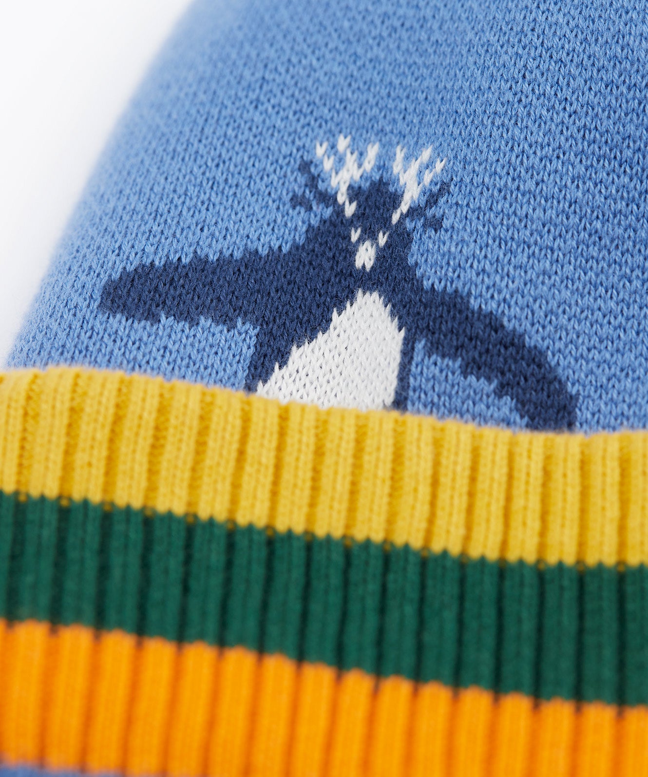 A close up of the Frugi reversible voyager hat showing the penguins design on blue GOTS organic cotton fabric with a yellow, green and orange soft ribbed trim