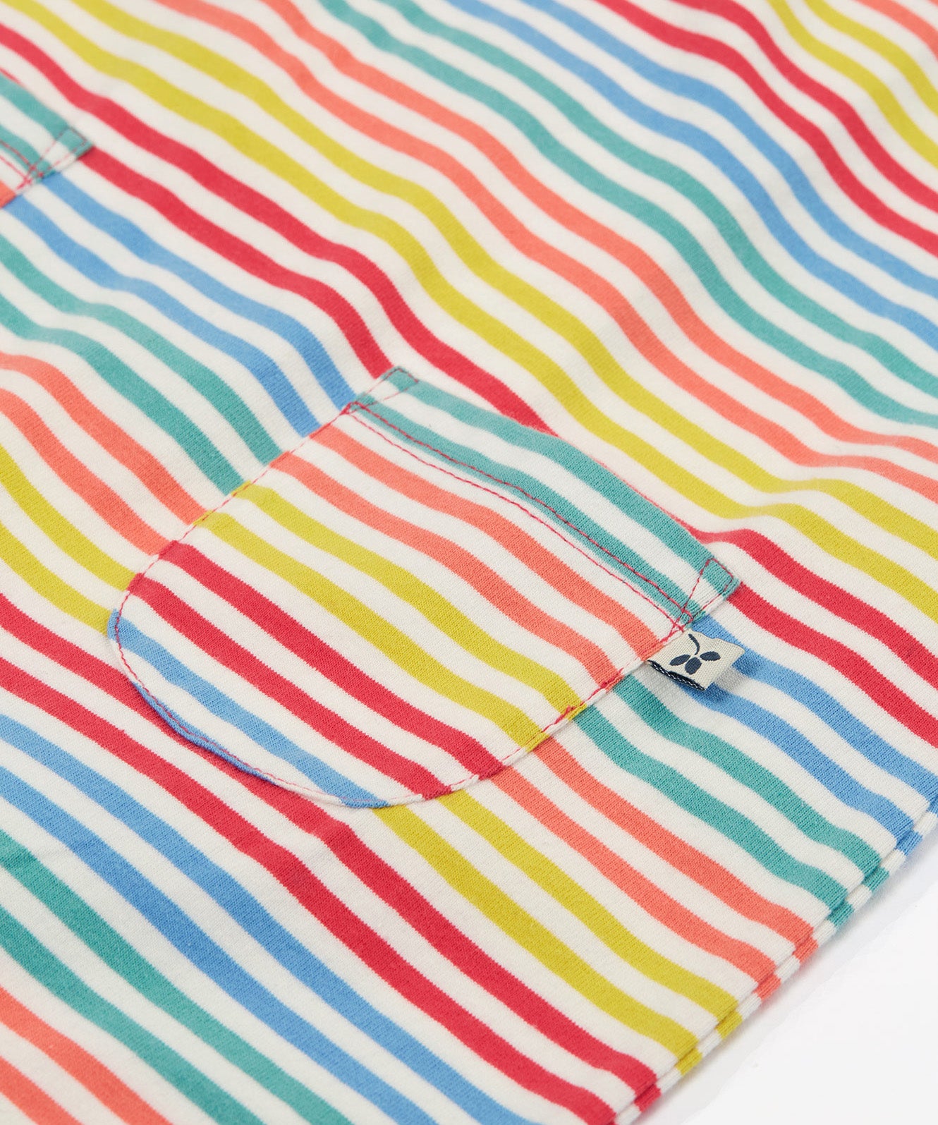 Close up of the Frugi kids cornflower rainbow stripe playsuit showing the small pocket detail on the front on striped organic cotton fabric.