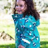 A side view of a toddler wearing the Frugi panda play light blue puddle buster coat showing the elasticated arm cuff detail and print detail
