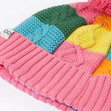A close up of the Frugi kids cable knit rainbow check bobble hat. Showing the thick cable knit and pink turned up cuff