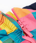 A close up of the Frugi rainbow check snow and ski salopettes showing the pink zip attaching the shoulder straps and bib to the trousers.