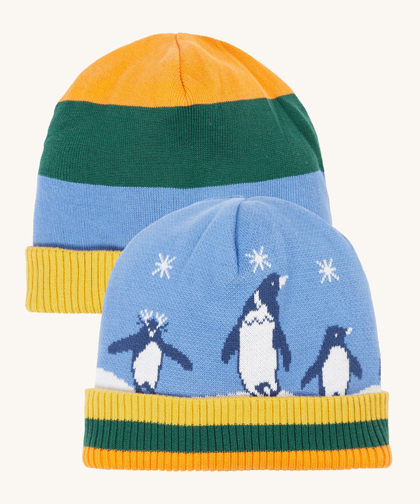Frugi reversible voyager hat in penguin/ rainbow. A GOTS organic cotton cosy hat with a cute penguin design on blue with a yelow, green and orange striped ribbed trim and a matching bold stripe on the reverse side.