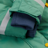 A close up of the Frugi kids snow and ski coat in green with a mountain scene print. Showing the extended navy arm cuffs for warmth and velcro detail for size adjustment.