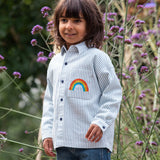 Frugi kids shacket, shirt with blue and white stripes and rainbow design worn by a child