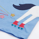 Back view of the Frugi Elise Wrap Around T-Shirt in cornflower blue – featuring the back of the white horse appliqué with roller skates and embroidered stars and trails. Made from GOTS organic cotton