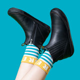 A child wearing the Frugi lake easy on child's leather shoe boots in black. with blue and white striped Frugi organic cotton socks.