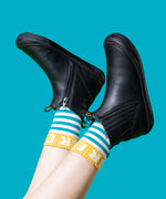 A child wearing the Frugi lake easy on child's leather shoe boots in black. with blue and white striped Frugi organic cotton socks.