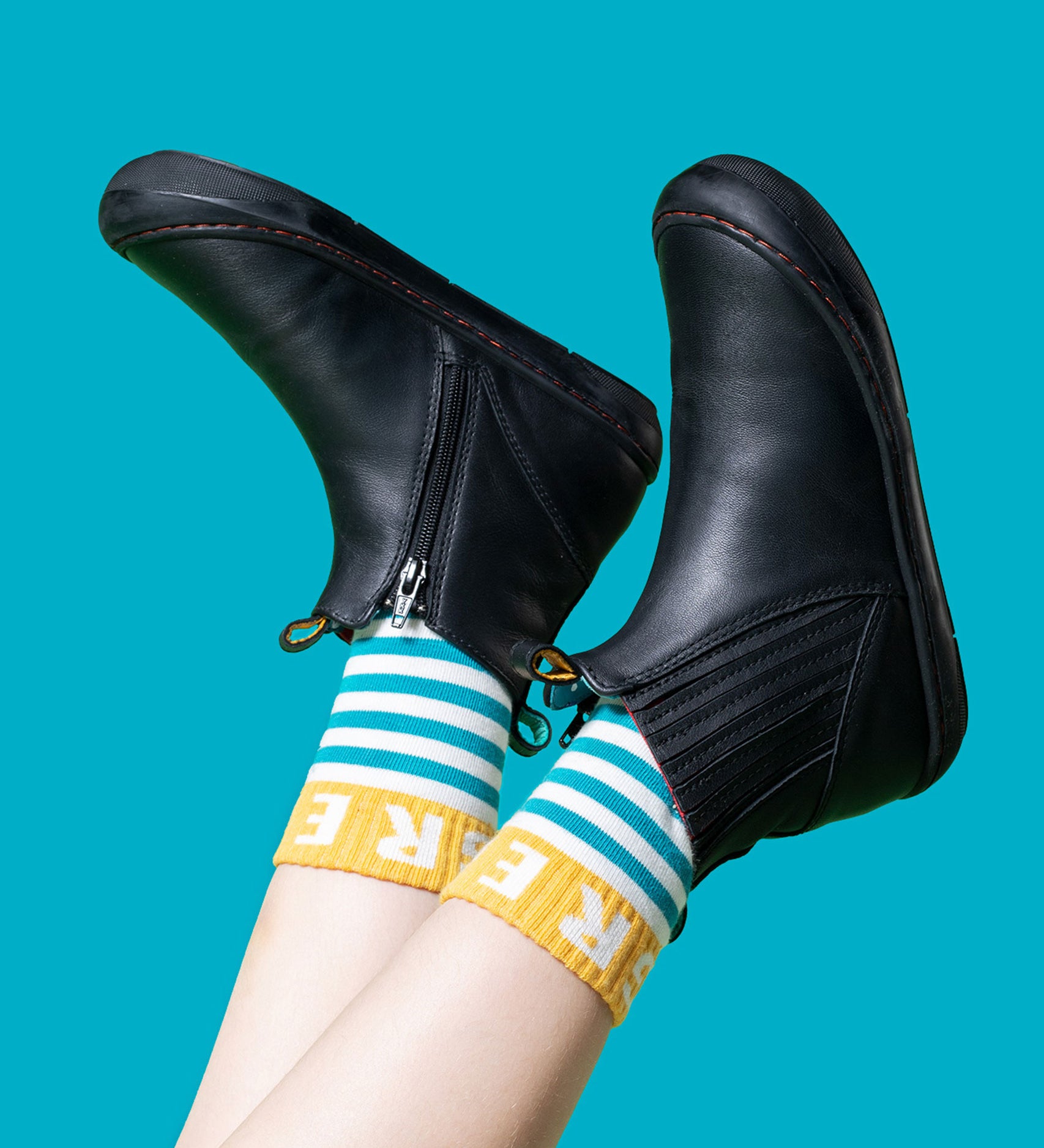 A child wearing the Frugi lake easy on child's leather shoe boots in black. with blue and white striped Frugi organic cotton socks.