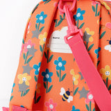 A close up of the Frugi little adventures fun flowers backpack showing the name tag on the back of the bag and the handy pink rein clip detail