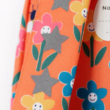 A close up of the shoulder strap of the Frugi little adventures fun flowers backpack showing the reflective stars and flower print detail