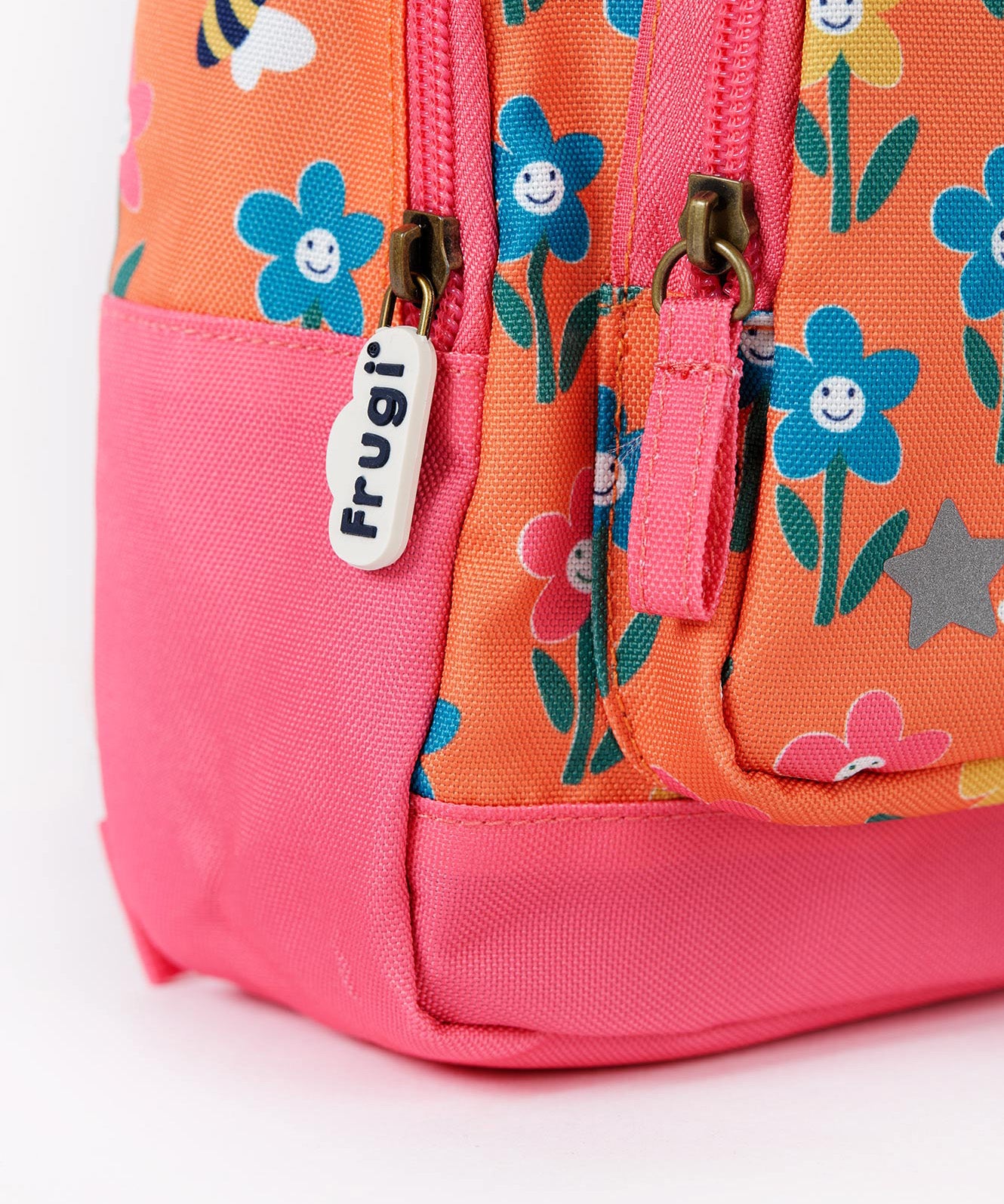 A close up of the bottom of the Frugi little adventures fun flowers backpack showing the zip detail and pink trim.