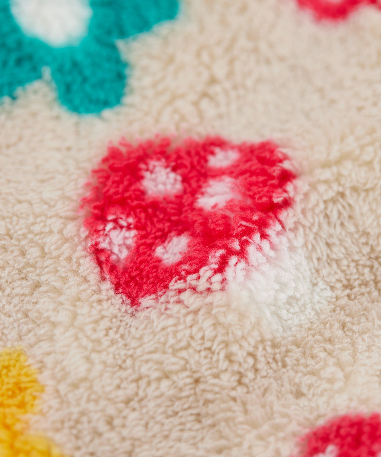 A close up o the Frugi kids recycled cosy snuggle suit in mushroom fields showing the mushroom design on a cream fleece style recycled fabric.