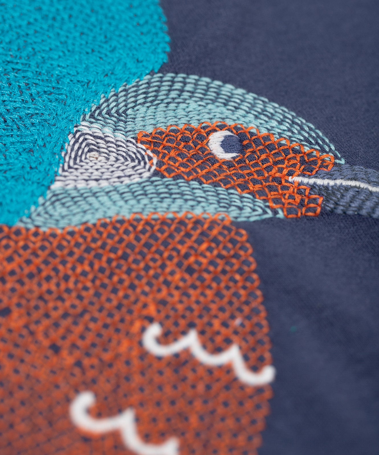 A super zoomed in view of the embroidered kingfisher detail on the front of the Frugi navy kingfisher Organic Cotton Embroidered long sleeve children's Top. This top is a part of a wide range of organic cotton clothing for children available here at Babipur.