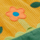 A close up of the flower applique detailing on the skirt of the Frugi Nellie Organic Cotton yellow gold Corduroy Pinafore Dress with Flowers. This dress is a part of a wide range of organic cotton clothing for children available here at Babipur.