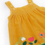 A close up of the front of the Frugi Nellie Organic Cotton yellow gold Corduroy Pinafore Dress with Flowers. This dress is a part of a wide range of organic cotton clothing for children available here at Babipur.