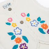 A close up of the embroidered flowers on the front of the Frugi Oatmeal Flowers Connie Cotton Knitted Sleeveless Cardigan. This white oatmeal sleeveless cardigan has cute scalloped edges and is decorated with pretty embroidered flowers and leaves on the front.  This waistcoat is a part of a wide range of organic cotton clothing for children available here at Babipur.
