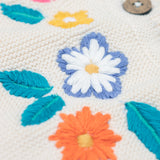 A close up of one of the embroidered flowers on the front of the Frugi Oatmeal Flowers Connie Cotton Knitted Sleeveless Cardigan. This white oatmeal sleeveless cardigan has cute scalloped edges and is decorated with pretty embroidered flowers and leaves on the front.  This waistcoat is a part of a wide range of organic cotton clothing for children available here at Babipur.