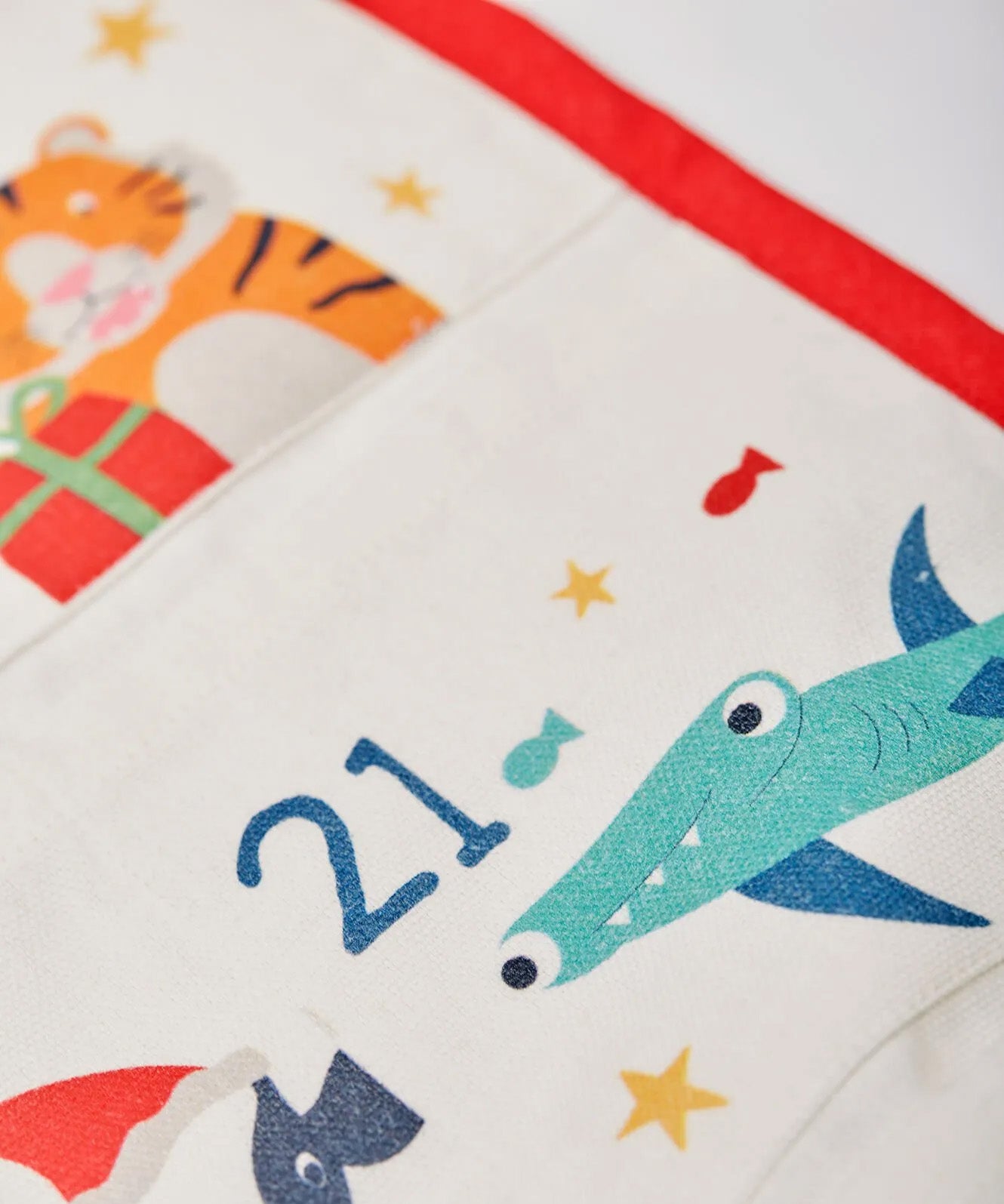 A closeup of The Frugi Organic cotton Christmas advent calendar, showing pouch for day 21 with a hammerhead shark illustration.