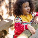 A child wearing the Frugi Festive Fair Isle Organic Cotton Kids' Carol Cardigan featuring red, yellow and green patterns and robin redbreast details. 
This knitted cardigan is a part of a wide range of organic cotton clothing for children available here at Babipur.
